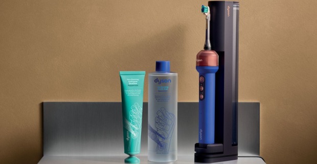Dyson Zahnbürste CameraJet mit KI und Kamera neben Ladestation, Dyson Zahnpasta und Mundspülung.