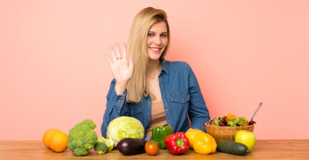 Frau zeigt fünf Finger vor Obst und Gemüse – fünf Fakten gegen Erkältung
