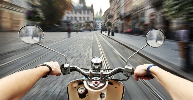 Mann, der auf dem Roller in alten Straßen der Stadt fährt.