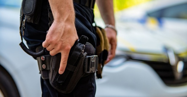 Ein Polizist zückt seine Dienstwaffe.