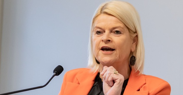 Verteidigungsministerin Klaudia Tanner in orangefarbenem Blazer spricht an einem Mikrofon zur Wehrdienstreform in Österreich.