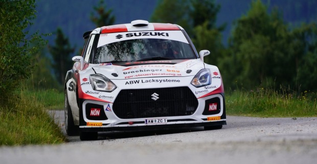Weiß-roter Suzuki Swift Rallyewagen auf einer Schotterstraße während einer Rallye. Das Foto illustriert den Motorsport, in dem Christina Ettel als Co-Pilotin aktiv ist.