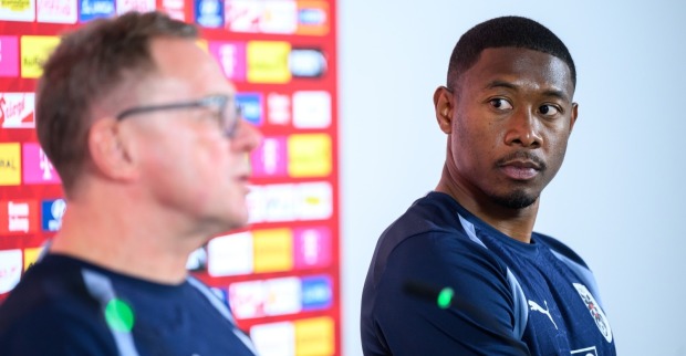 David Alaba sitzt im dunkelblauen ÖFB-Trainingsshirt bei einer Pressekonferenz und blickt zu einem Mann neben ihm.