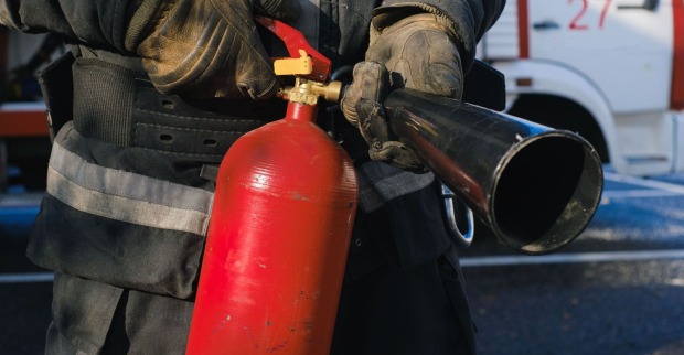 Feuerwehrmann mit Feuerlöscher im Einsatz – bei einem Großbrand in Obsteig in Tirol wurden fünf Feuerwehrleute leicht verletzt.
