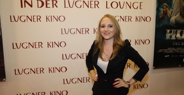 Jacqueline „Jacky“ Lugner posiert vor einer Fotowand des Lugner Kinos in Wien. Die Geschäftsführerin der Lugner City feiert einen historischen Umsatzrekord.