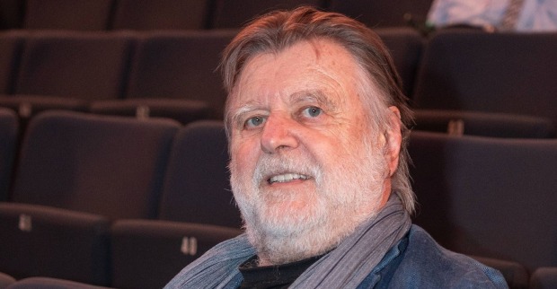 Lukas Resetarits mit grauem Bart und Schal in einem Theatersaal. Der Kabarettist beendet nach 49 Jahren seine Bühnenkarriere.