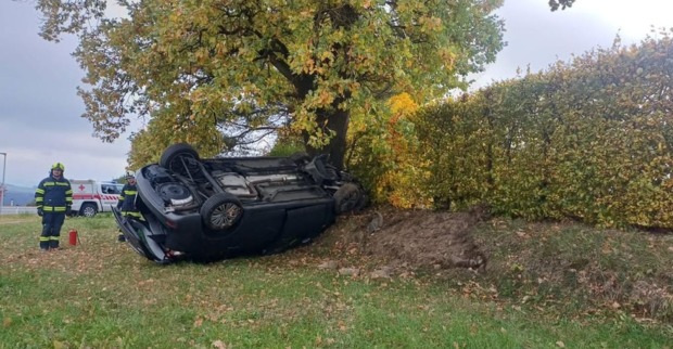 Überschlagenes schwarzes Auto liegt nach einem Unfall auf der B 125 bei Neumarkt im Mühlkreis auf dem Dach neben einem Baum. Feuerwehrkräfte stehen an der Unfallstelle.