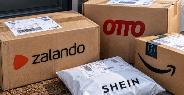 KI-generiertes Symbolbild mit Versandpaketen von Zalando, Otto und Amazon sowie einer Shein-Sendung vor einer Haustür. Die Pakete stehen für den Rechtsstreit um die österreichische Paketsteuer.