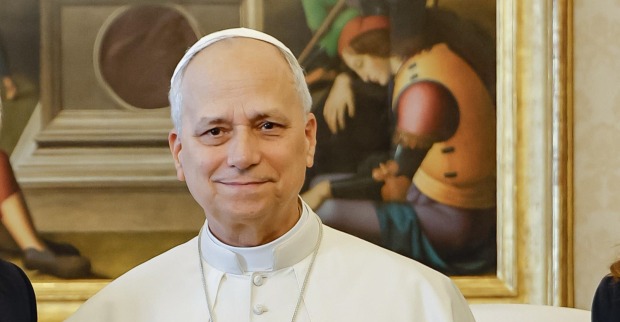 Papst Leo XIV. lächelt in weißem Papstgewand und weißer Kappe vor einem Gemälde. Sein Gesundheitszustand nach der Krebsoperation steht im Fokus.