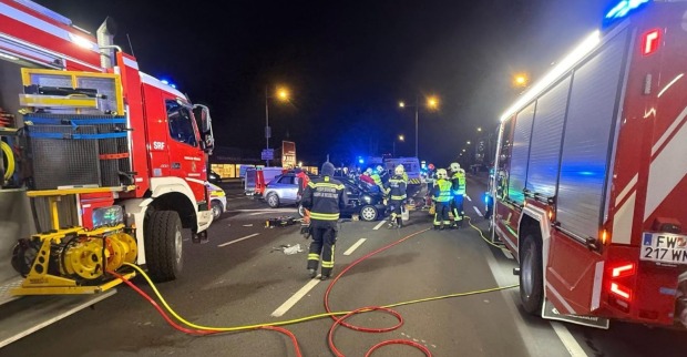 Feuerwehrkräfte und Rettungsfahrzeuge bei einem nächtlichen Verkehrsunfall auf der B17 in Wiener Neustadt. Zwei Feuerwehrautos sichern die Unfallstelle ab.