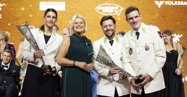 Drei Sporthilfegala-Sieger und Verteidigungsministerin Claudia Tanner vor einem gold-gelben Hintergrund