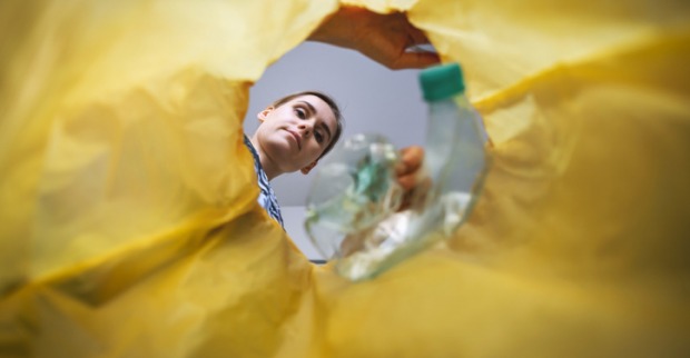 Frau entsorgt Plastik im Müllsack