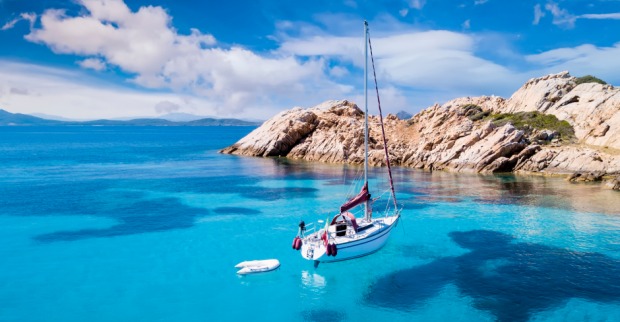 Ein kleines Boot liegt an einem sonnigen Sommertag vor der Küste Sardiniens | Credit: iStock.com/Travel Wild
