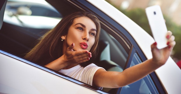 Frau erstellt ein Selfies und wirft einen Kussmund in Richtung Smartphone-Kamera | Credit: iStock.com/NiKita Filippov