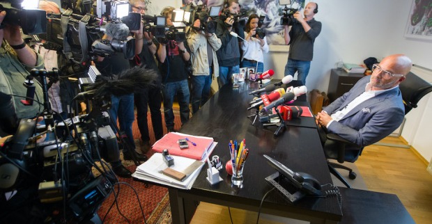 Presseleute umringen den Anwalt, er sitzt auf einem Sessel hinter seinem Schreibtisch