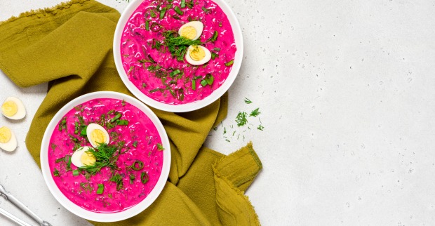 Zwei pinkfarbene kalte Suppen in weißen Schalen auf einer zerknüllten grünen Tischdecke