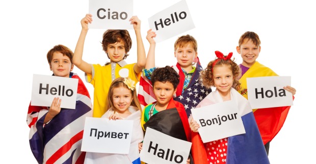 Kinder, die auf Schildern das Wort "Hallo" in verschiedenen Sprachen präsentieren