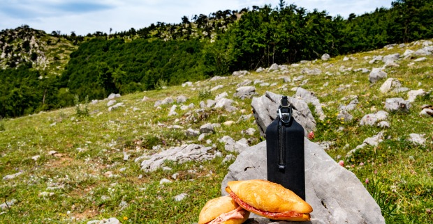 Zwei Brötchen mit einer Trinkflasche auf einem großen Stein in der Natur