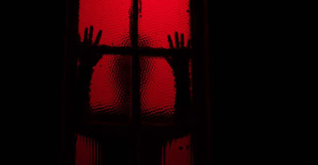 Schatten eines Menschen hinter einem rot erleuchteten Fenster | Credit: iStock.com/rushay booysen