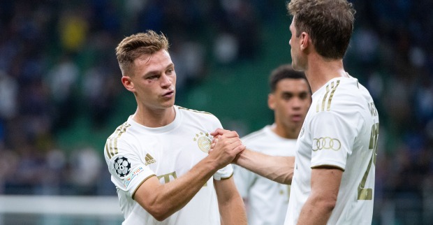 Die deutschen Nationalspieler Thomas Müller und Joshua Kimmich, die auf dem Fußballfeld einen Handschlag durchführen