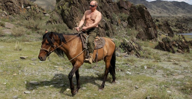 Putin mit nackten Oberkörper auf einem Pferd in den Bergen.
