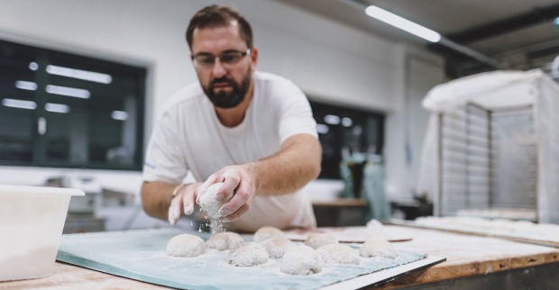 Blick in Brotproduktion, Bäcker formt Weckerl