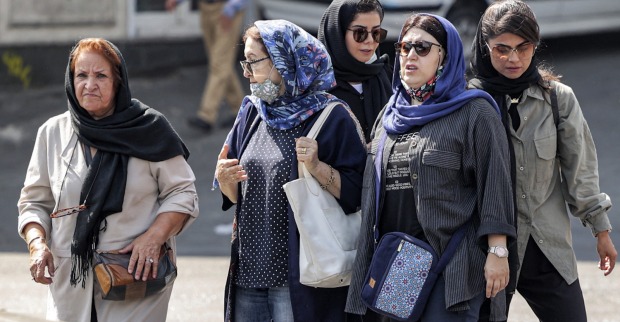 Eine Gruppe iranischer Frauen unterschiedlichen Alters, die Kopftücher tragen, auf der Straße einer iranischen Stadt