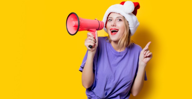 Frau mit rotem Megaphon und Weihnachtsmütze | Credit: iStock.com/Massonstock