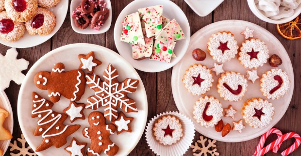 Ein Tisch, auf dem mehrere Teller mit unterschiedlichen Weihnachtssüßigkeiten stehen: Lebkuchen, Kekse, Zuckerstangen