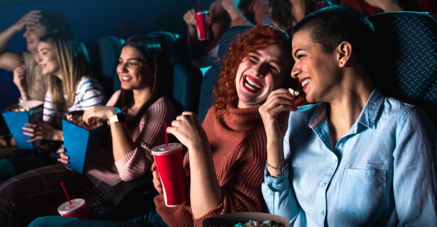 lachende Menschen essen Popcorn im Kino | Credit: iStock.com/Zoran Zeremski