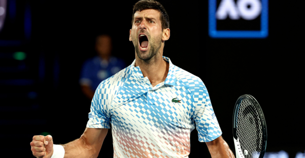 Der auf dem Tennisplatz jubelnde Novak Djokovic, der ein weißes Tennisdress mit einem blauen Karomuster trägt