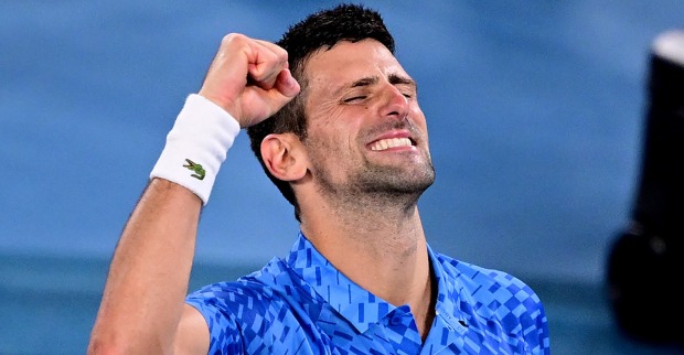 Der mit erhobener Faust auf dem Tennisplatz jubelnde Novak Djokovic, der ein blau karriertes Tennisdress trägt