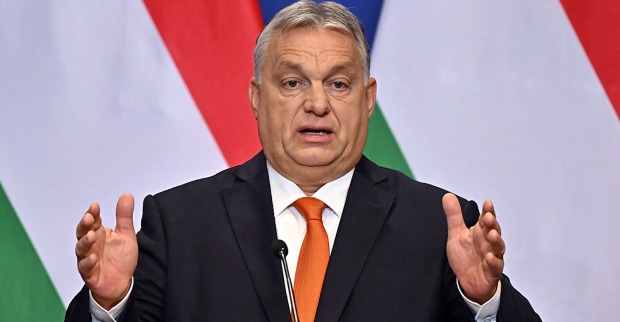 Der ungarische Premierminister Viktor Orban gestikuliert mit beiden Händen hinter einem Rednerpult vor zwei ungarischen Nationalfahnen